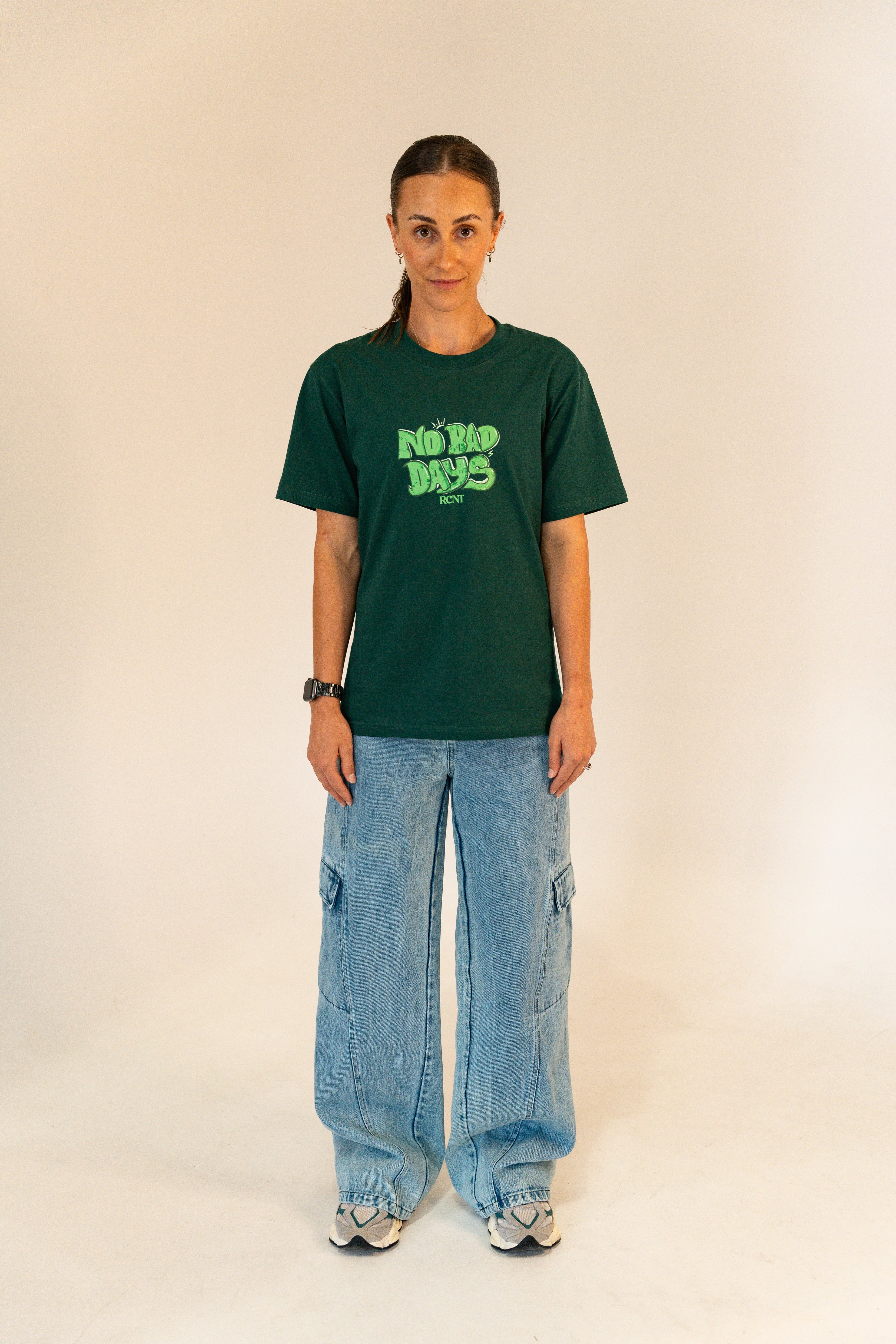 Woman wearing green graphic T-shirt with No Bad Days print, baggy cargo jeans, and sneakers