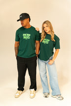 Man and woman wearing green "No Bad Days" graphic t-shirts with casual pants and sneakers