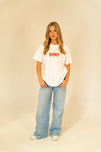 Young woman in casual white RCNT graphic t-shirt and wide-leg light blue jeans posing in studio