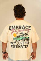 Man wearing cream t-shirt with vintage car and quote Embrace the journey, not just the destination