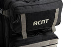 Close-up of black RCNT branded tactical backpack front pocket with gray straps and zipper pulls