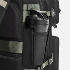 Black backpack with mesh water bottle holder containing a black shaker bottle and green straps