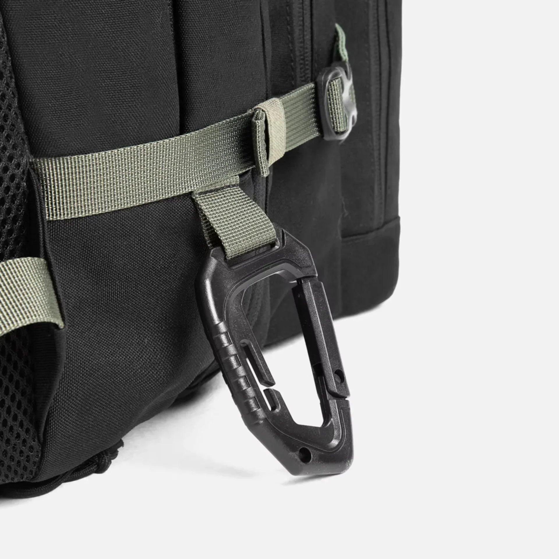 Black backpack with green straps and attached black carabiner clip close-up
