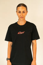 Woman with tied-back hair wearing black t-shirt with red text 'ROOT EST 2022' on plain background