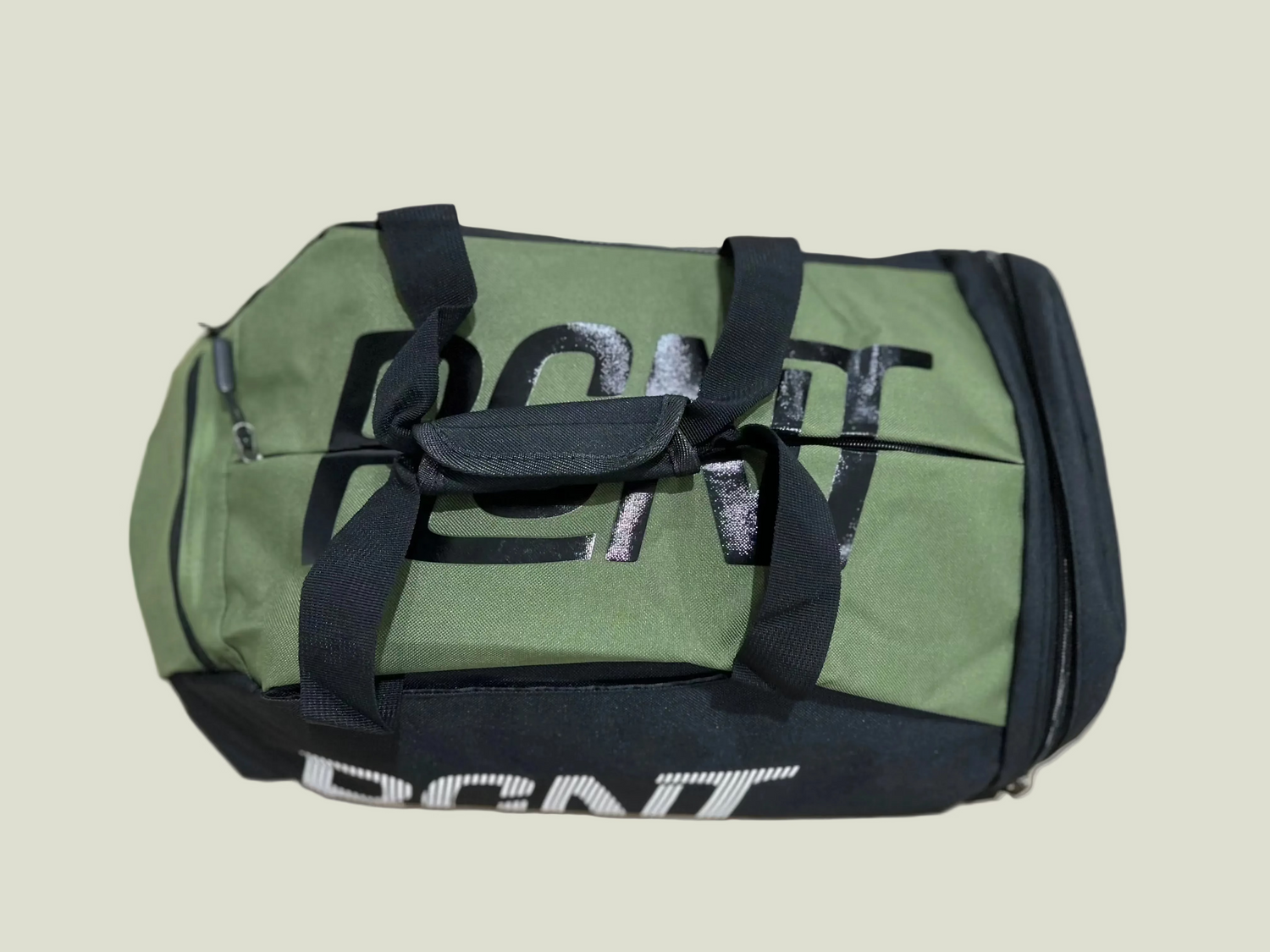 Green duffel bag with black straps on a biege background