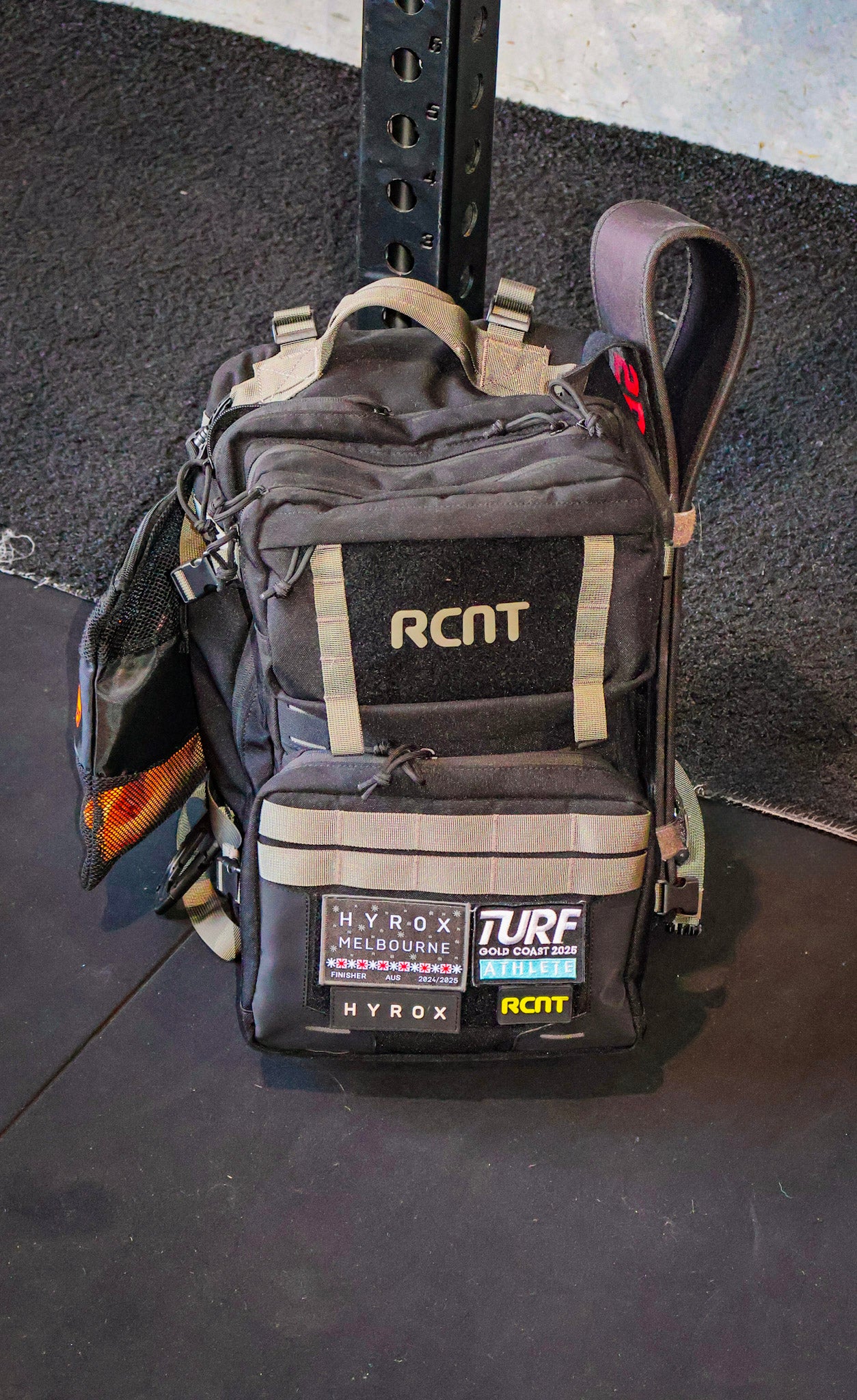 Black RCNT gym backpack with Melbourne and athlete patches on gym floor