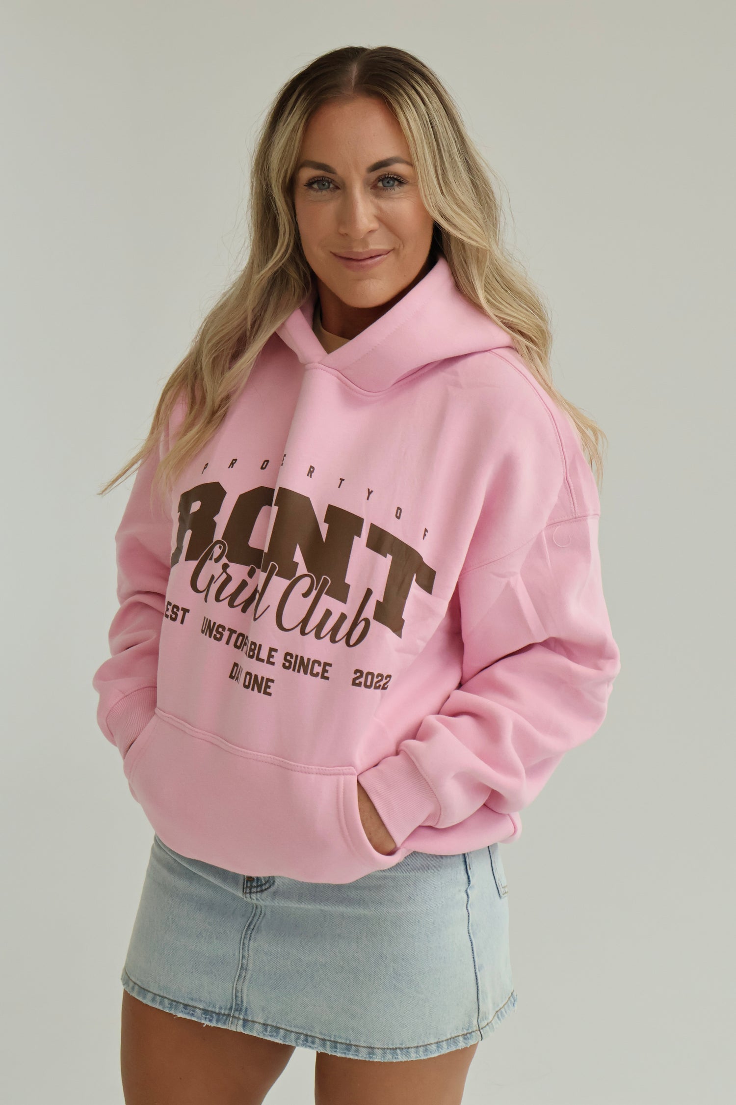 Woman wearing a pink hoodie with text on a plain background