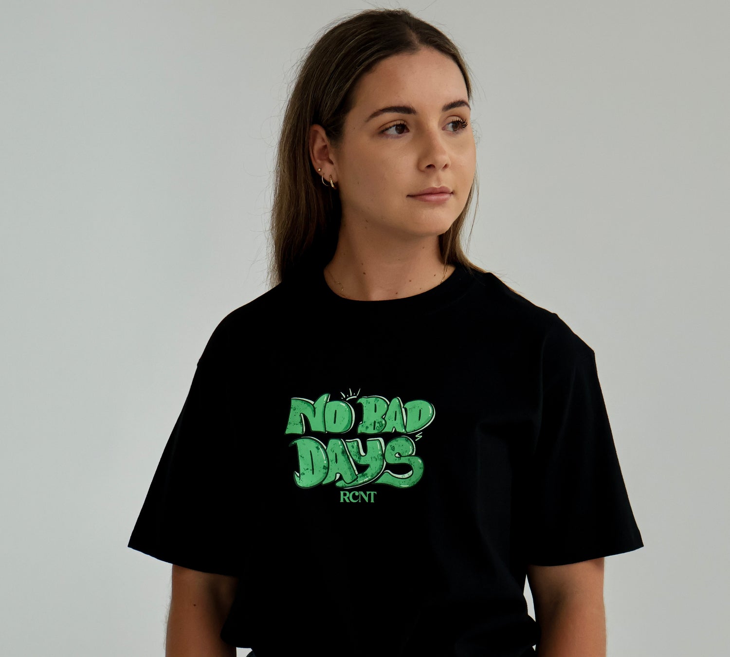 Woman wearing black t-shirt with green 'No Bad Days RCNT' graphic, casual stylewear