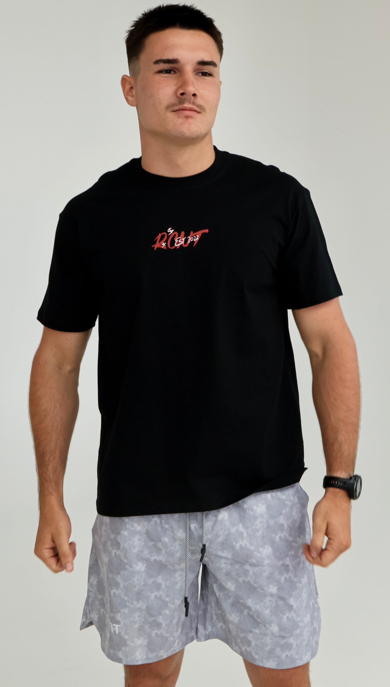 Man wearing black graphic t-shirt and light gray camo shorts, casual stylewear