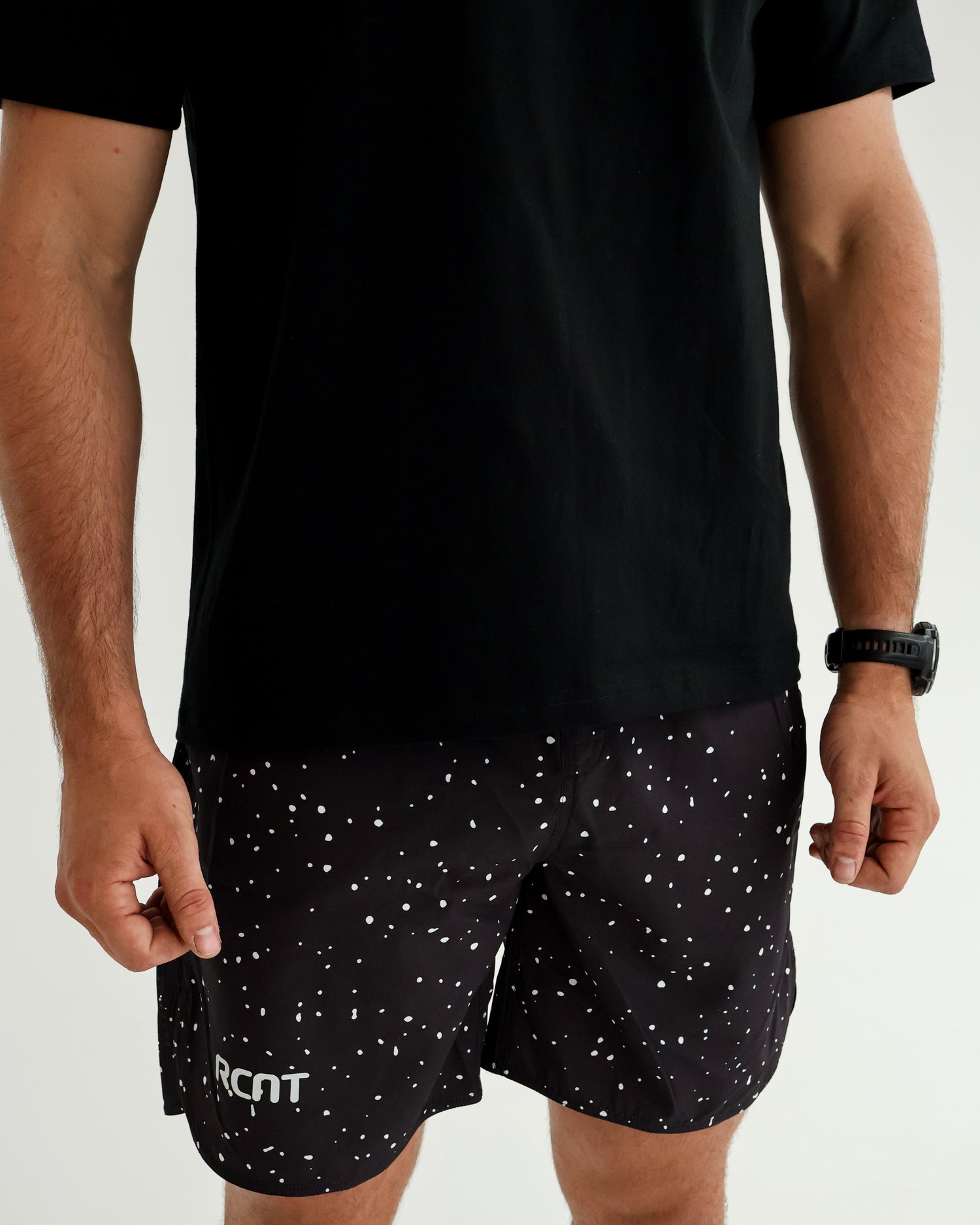 Man wearing black speckled shorts with RCNT logo and a black t-shirt