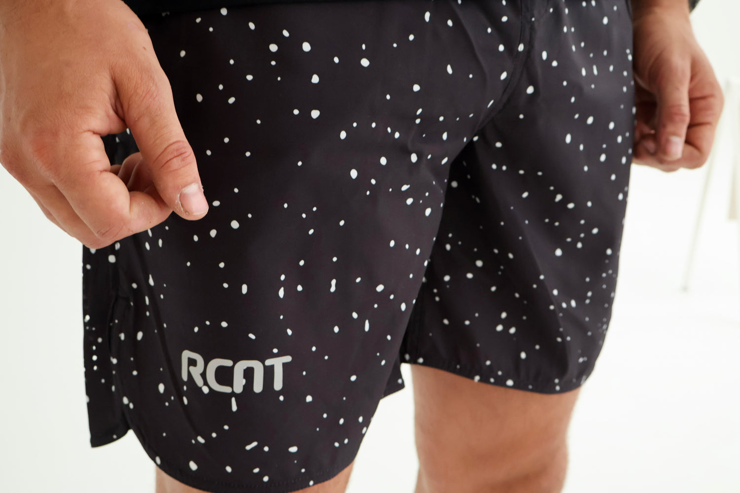 Black athletic shorts with white dot pattern and RCNT logo, worn by a person