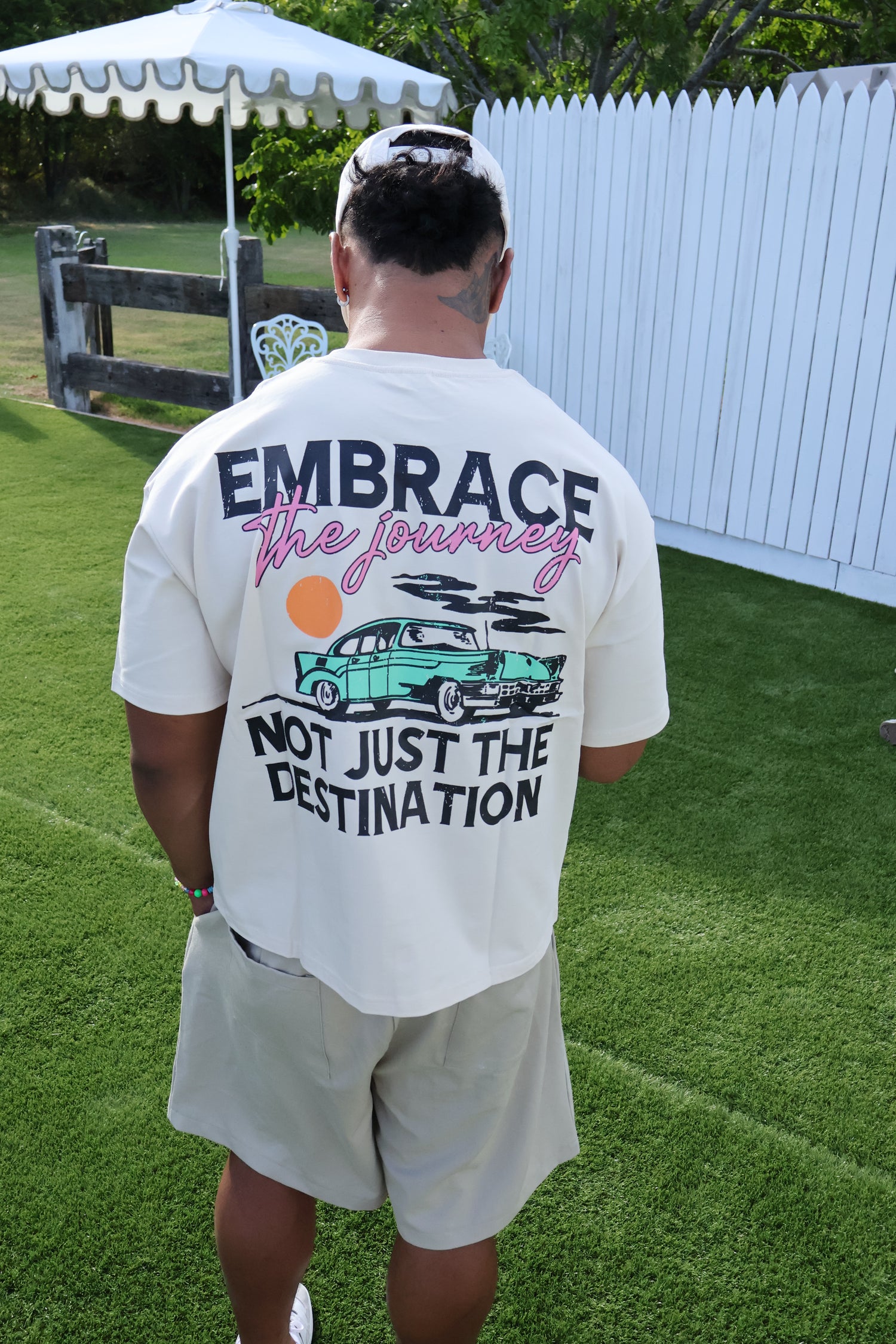 Man outdoors wearing beige shirt with graphic text 'Embrace the journey not just the destination'.