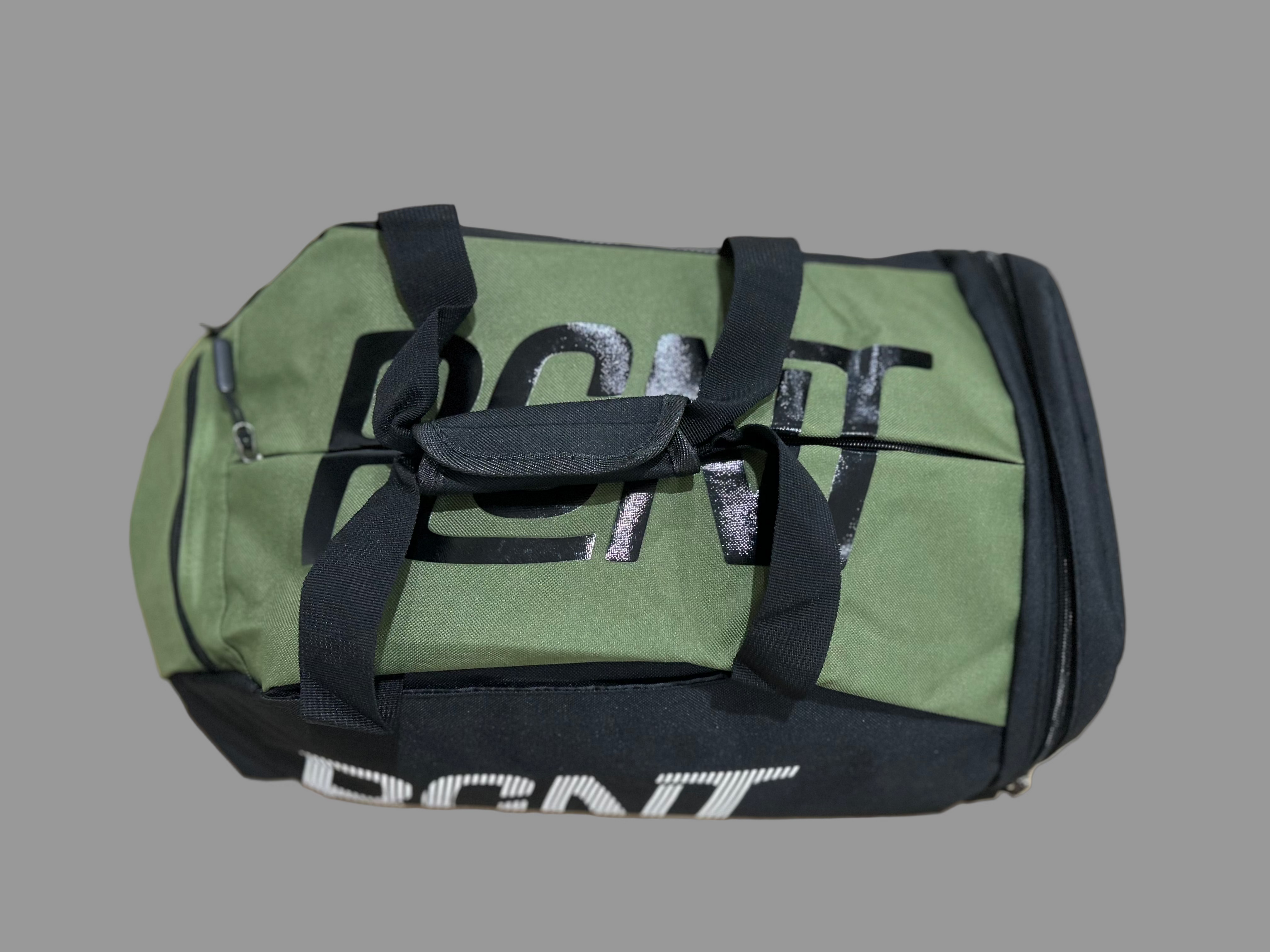 Green duffel bag with black straps on a light wooden surface
