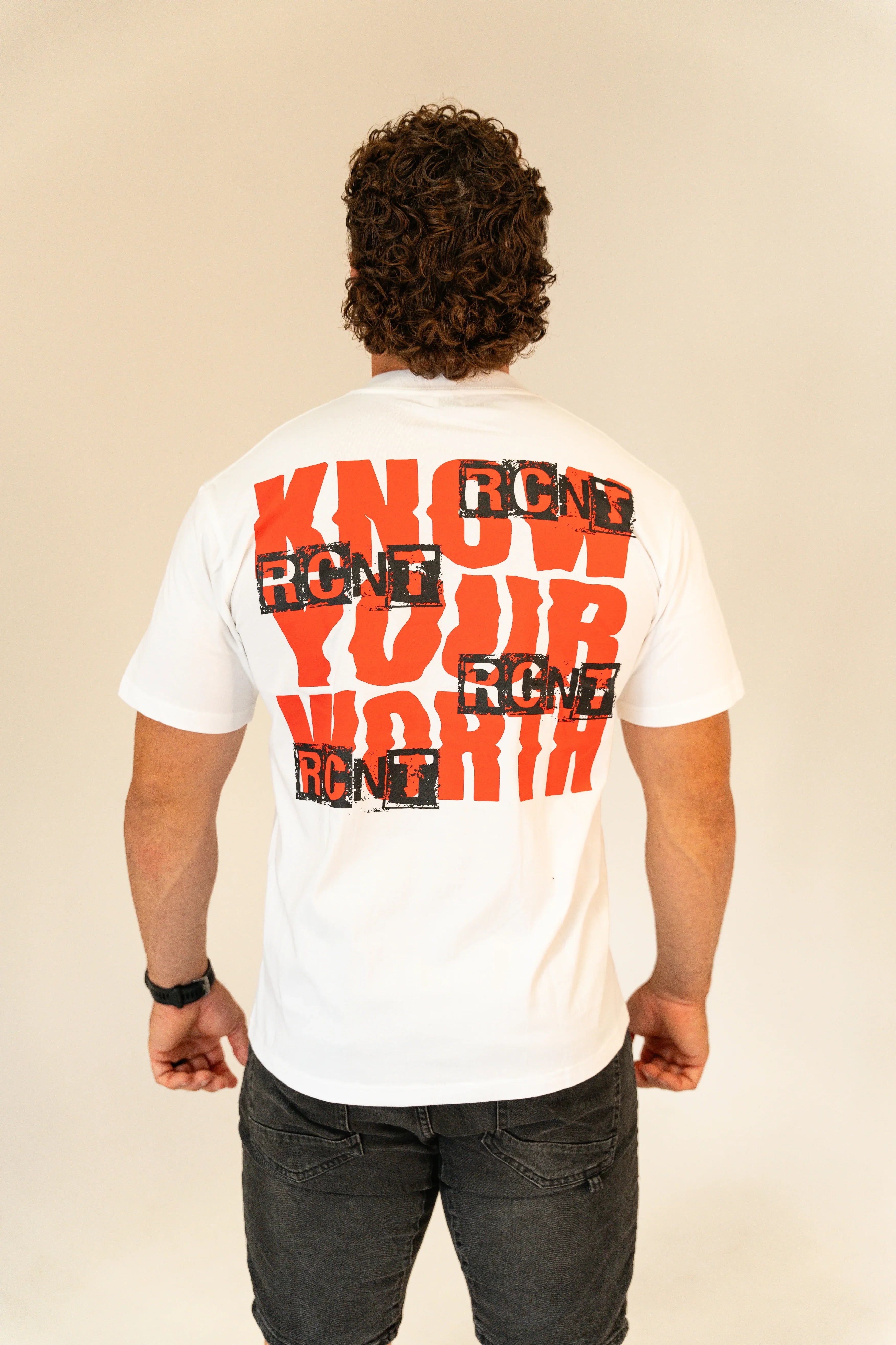Man wearing white t-shirt with bold red and black 'Know Your Worth' graphic on back