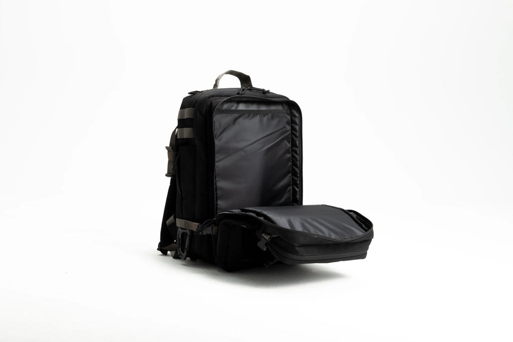 Black tactical backpack open with padded compartments on white background