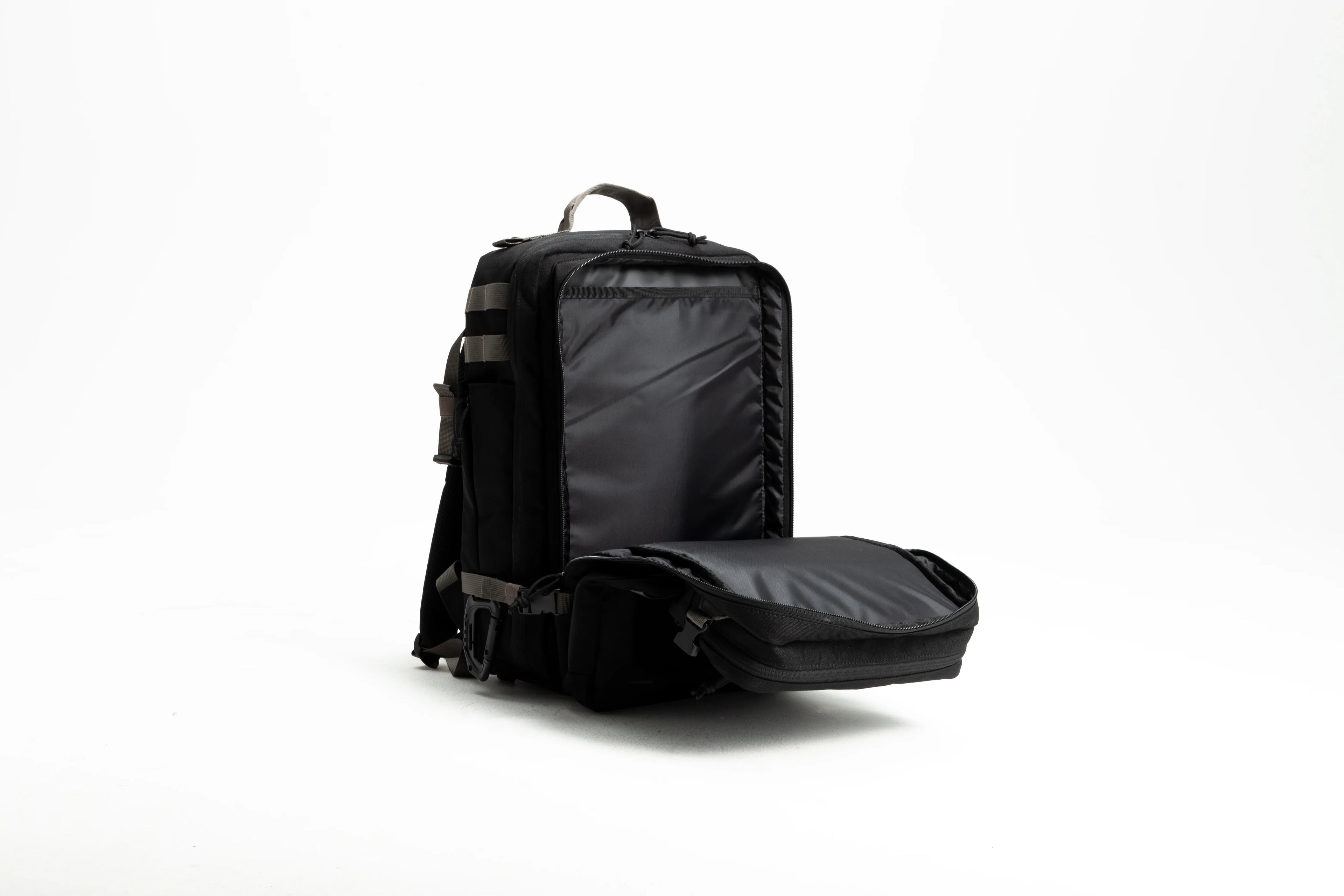 Black tactical backpack open with padded compartments on white background