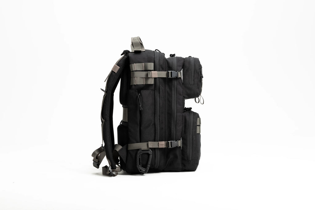 Side view of black tactical backpack with multiple compartments and adjustable straps on white background