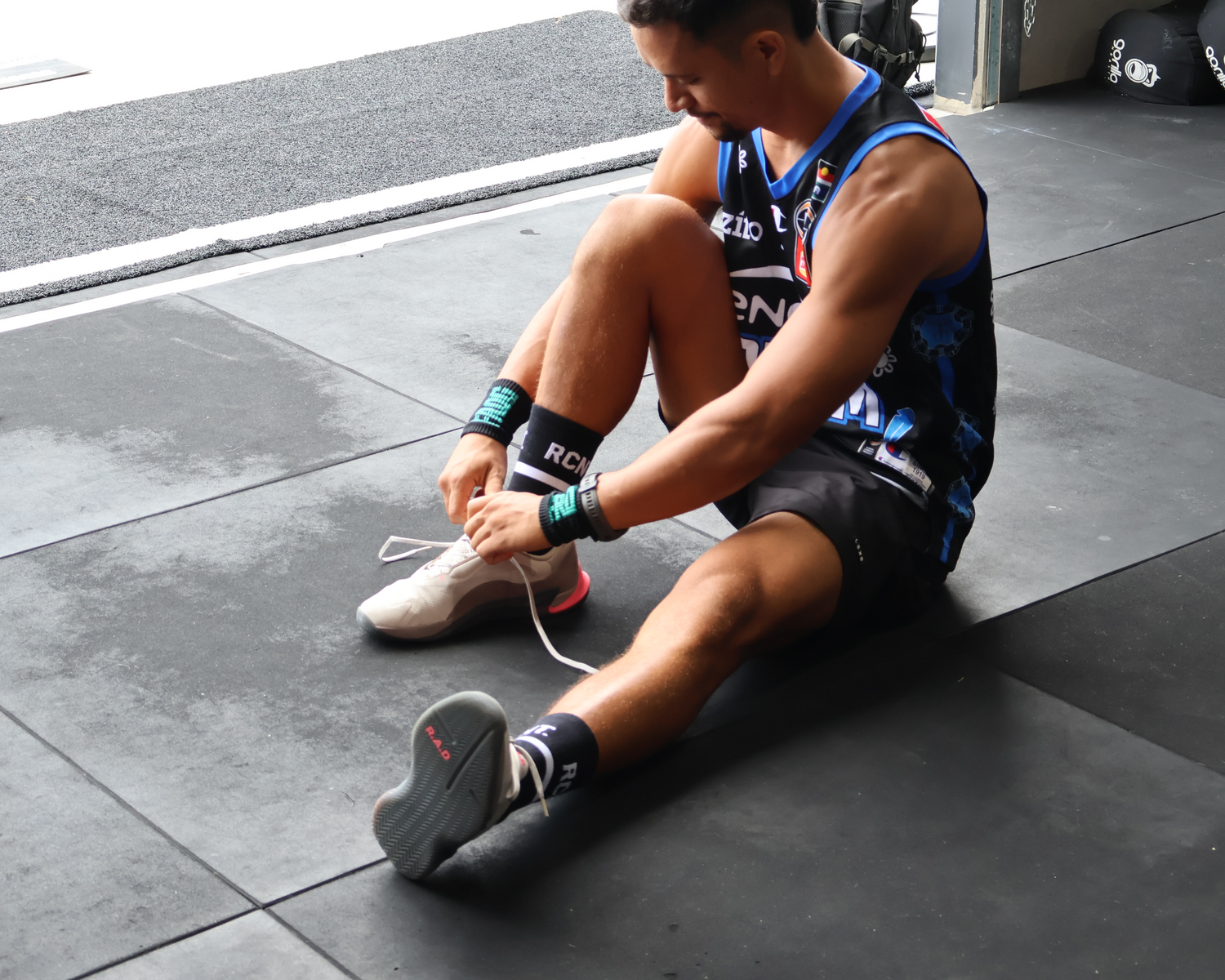 Person tying shoelaces on a gym floor