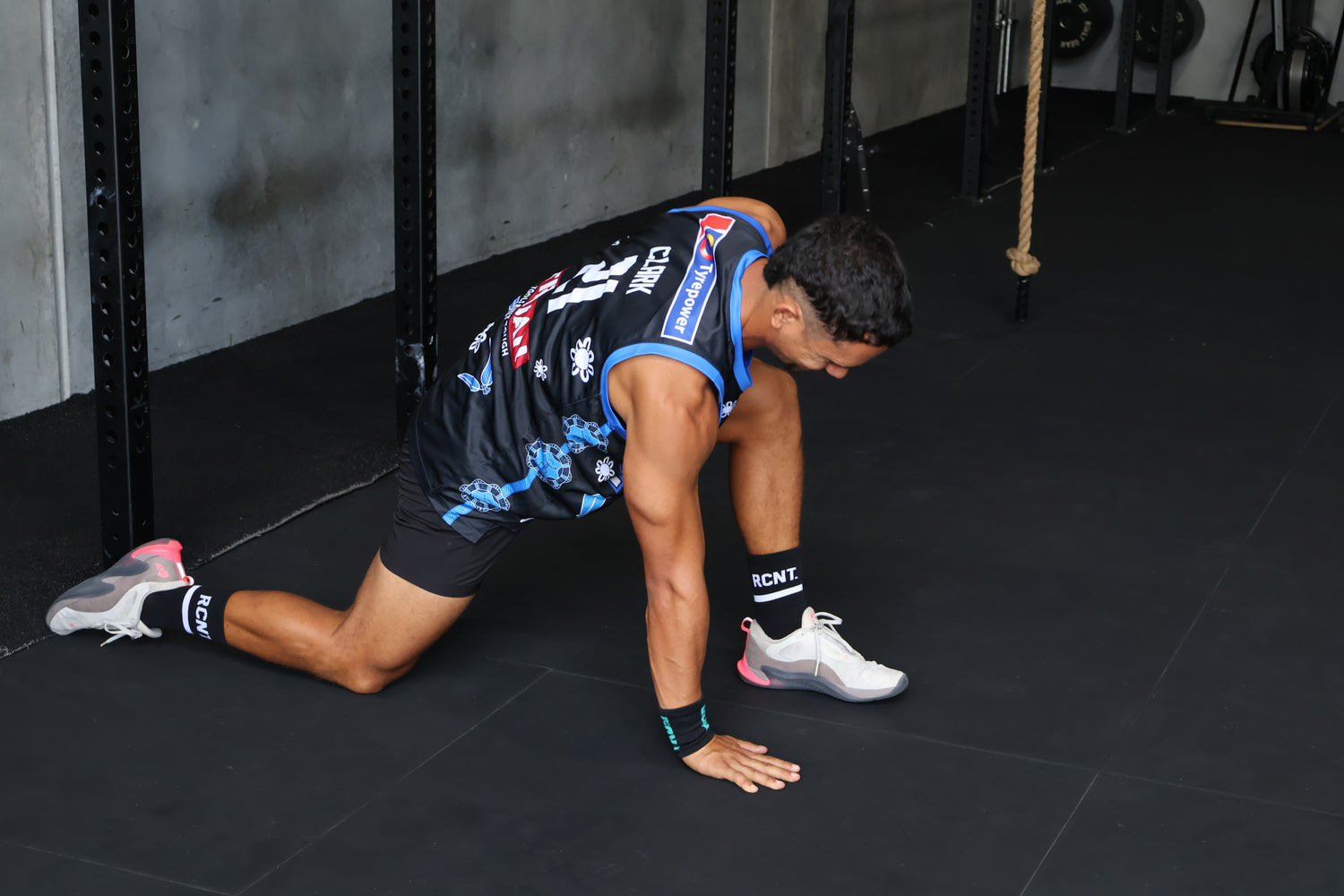 Athlete stretching in gym wearing black RCNT sport socks and sneakers